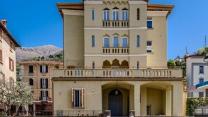 A multi-story building with a symmetrical facade, large windows, and a central entrance with an archway. - Lovely apartment for 4 guests with A/C, WIFI, patio and pets allowed (Bellano)