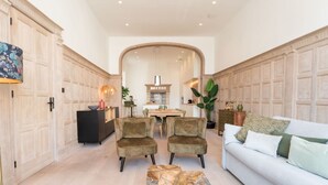 Un salon spacieux comprenant un canapé, deux fauteuils, une table basse et, au fond, un coin repas.
