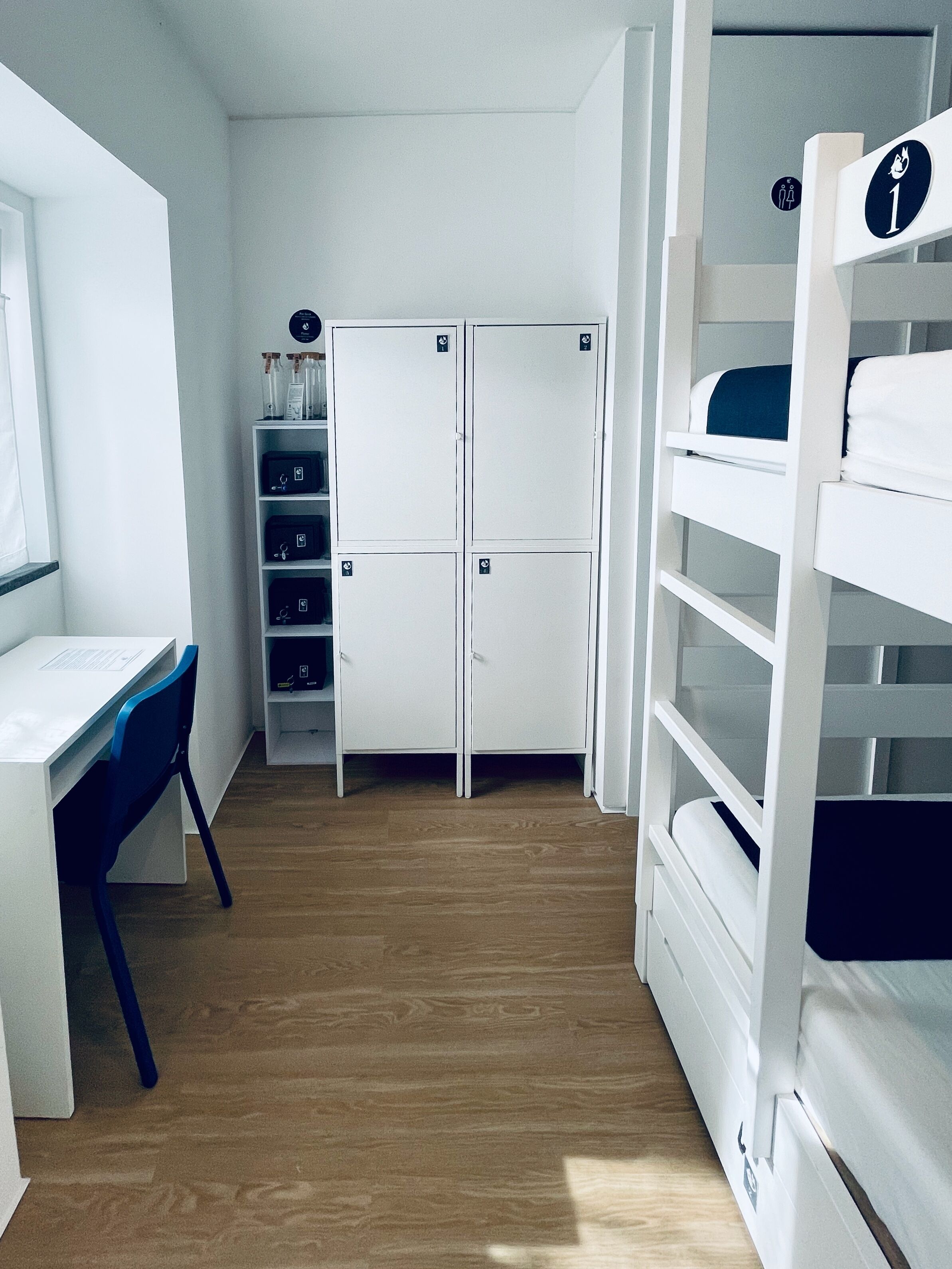 Een kleine kamer met een stapelbed, een bureau en een kledingkast.