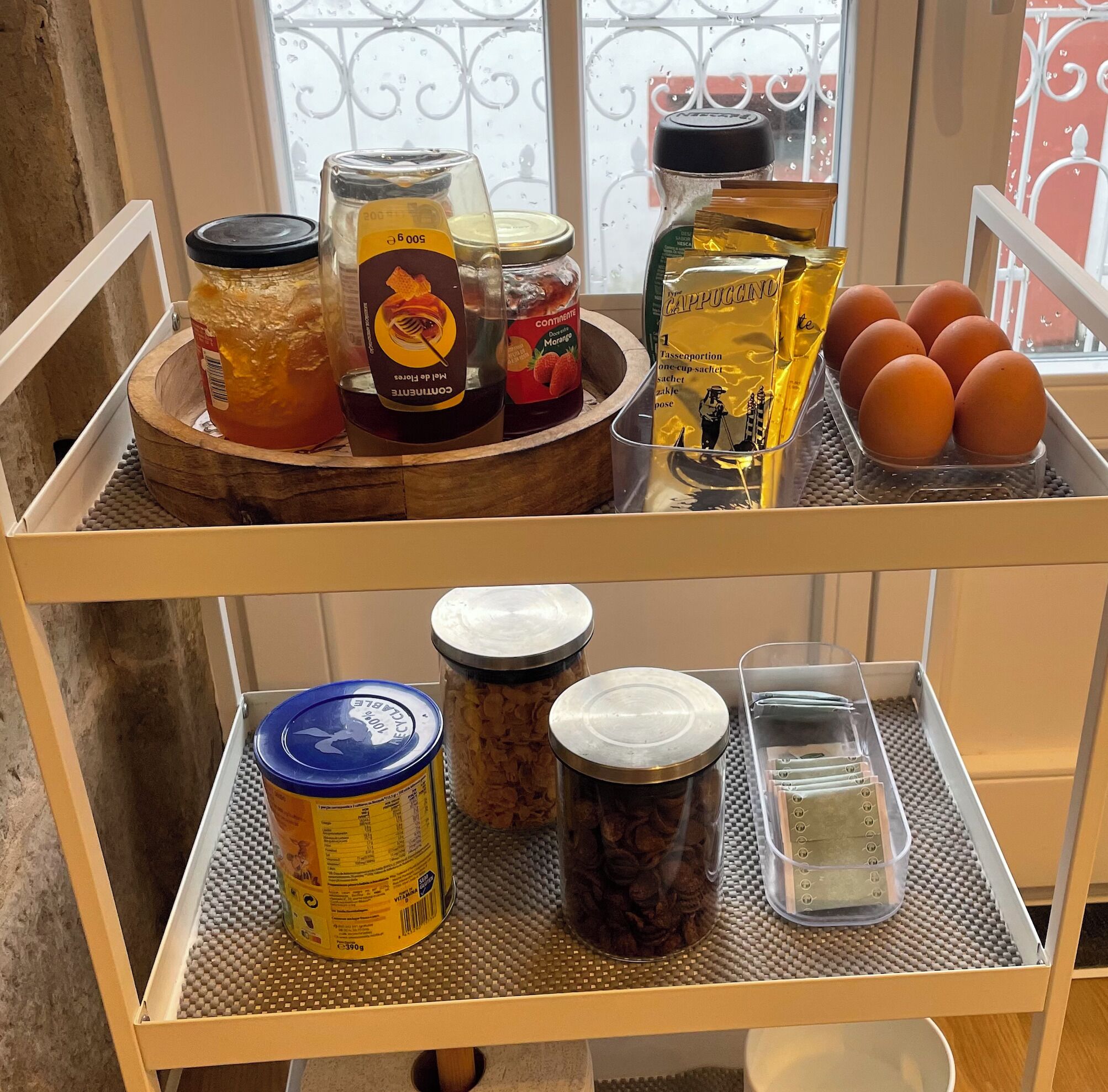 Una estantería de cocina con frascos de miel, mermelada y café, además de huevos y una cafetera.