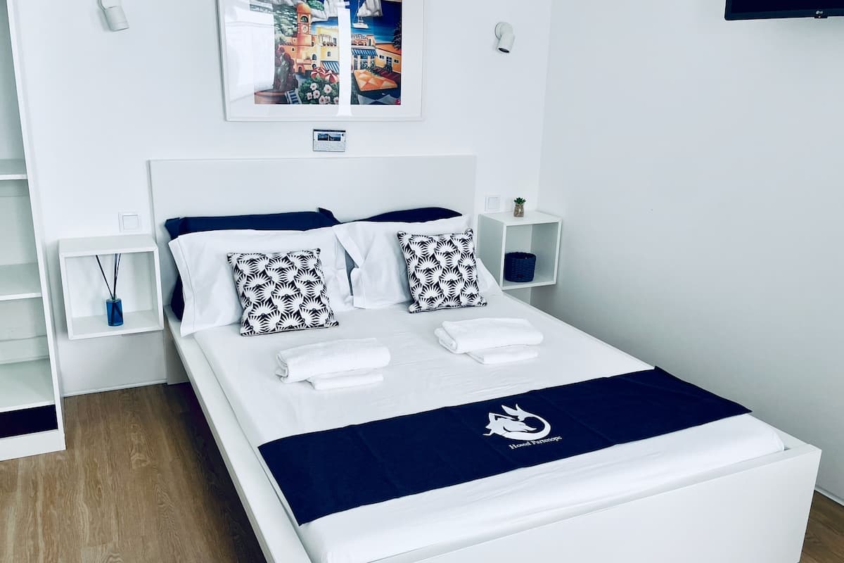 A modern hotel room with a white bed, navy blue bedding, and a decorative pillow.