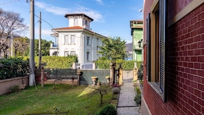 A residential area with a white house, a red brick building, and a well-maintained garden. - Wonderful  villa for 8 guests with WIFI, TV and balcony (Porto Ceresio)