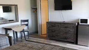 A room with a bed, a dresser, a TV, and a microwave. - Motel 81 (Dalton)