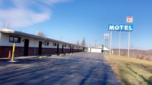 A motel with a parking lot, a building with a flat roof, and a sign indicating the motel is on route 81. - Motel 81 (Dalton)