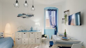 A bedroom with a bed, dresser, bedside table, lamp, and a TV.
