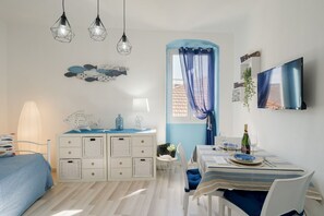 Une chambre à coucher comprenant un lit, une commode, une table de chevet, une lampe et un téléviseur.