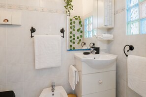 Ein Badezimmer mit Waschbecken, Spiegel, Handtuchhalter und einer Pflanze.