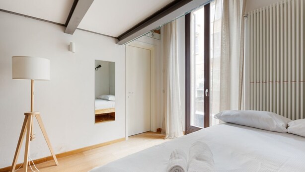 A hotel room with a bed, a standing lamp, a mirror, and a view of the outside. - GuestHost - Apartment on 2 levels Milan-Crocetta M3! (Milano)