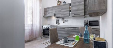 Una cocina moderna con armarios grises, una mesa de comedor con un posavasos y una botella azul.