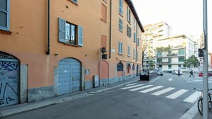 A street view with a building featuring a crosswalk, a bicycle, and a pedestrian.