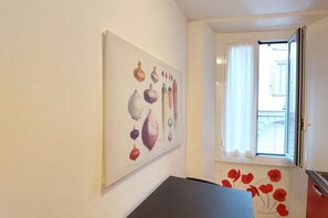 Ein Flur mit einem Gemüsebild an der Wand, einer Tür, die auf einen Balkon führt, und einer roten Mohnblumen-Dekoration auf dem Boden.