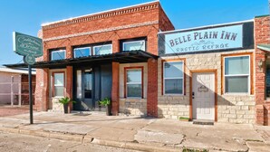 A two-story building with a brick facade, a sign for Belle Plain Inn, and a storefront with a metal awning. - Belle Plain Inn Rustic Refuge (Baird)