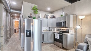A modern kitchen with stainless steel appliances, grey cabinets, and a built-in oven. - Belle Plain Inn Rustic Refuge (Baird)