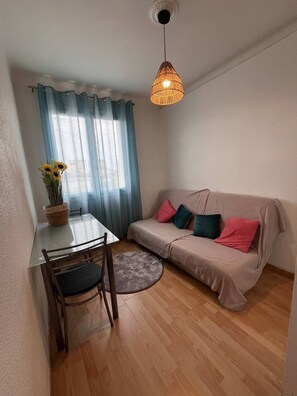 Cozy living space with a dining area and seating area, featuring a table, chairs, and a sofa with cushions.