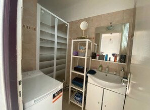 Compact bathroom with a sink, mirror, and shelving unit.
