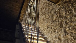 Una escalera de madera con un muro de piedra de fondo.