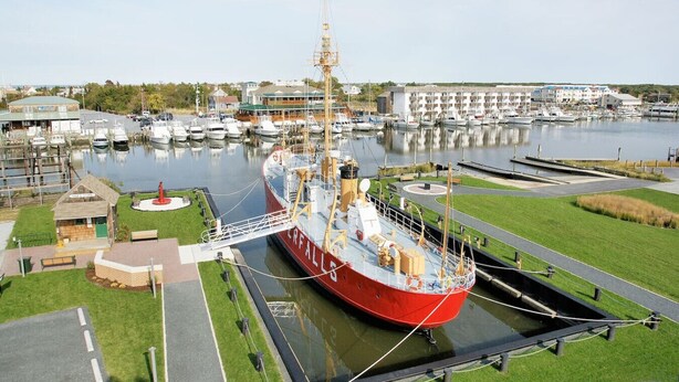A large ship docked at a marina with a grassy area and a small building nearby. - Beach Retreat: Easy Walkable Living w/ Bikes & Coffee (Lewes)
