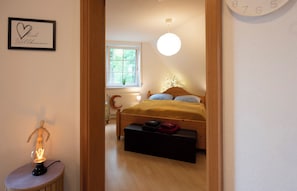 Un dormitorio con cama, mesita de noche y un reloj de pared.