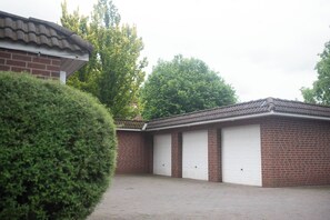 A building with two garage doors, a brick exterior, and a gravel driveway. - Cozy heath idyll in the countryside (Schneverdingen)