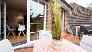 A patio area with a table and chairs, a potted plant, and a view of the house's interior through a glass door. - Cozy heath idyll in the countryside (Schneverdingen)