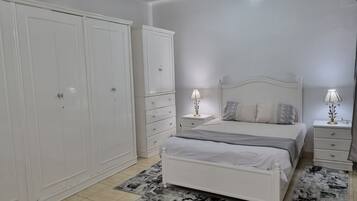 Un dormitorio con cama, mesitas de noche, un armario y una alfombra estampada.