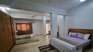 Un dormitorio con cama, ventilador de techo, ventana con cortinas y puerta.