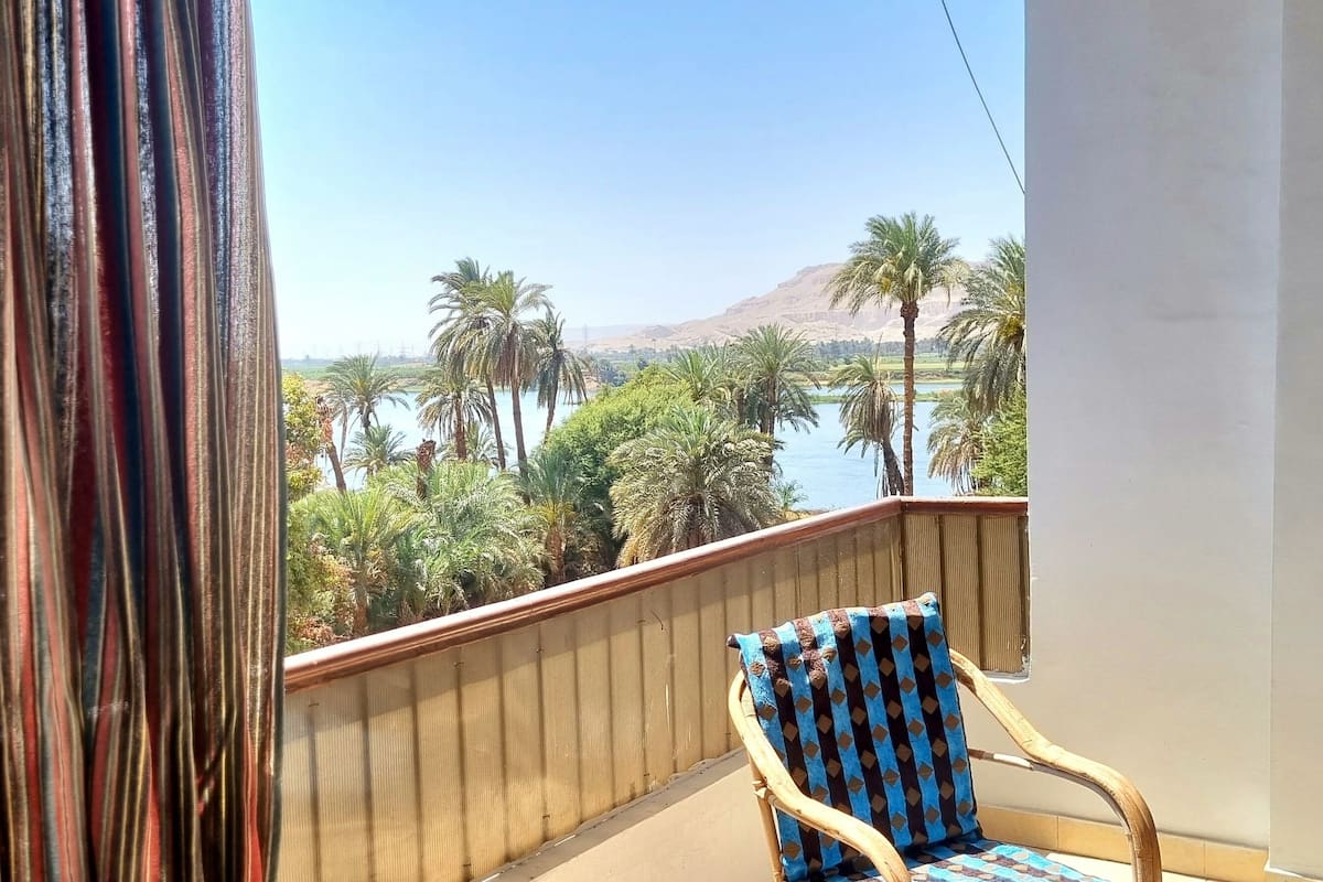 Ein Balkon mit Blick auf einen See, Palmen und ein Gebirge.