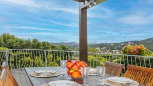 A wooden table set for dining with plates, cutlery, and a fruit bowl on a balcony with a scenic view. - Wonderful private villa for 6 people with private pool, WIFI, A/C, TV and terrace (Calonge)