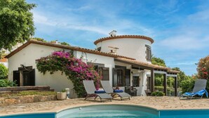 A poolside area with lounge chairs, a pergola, and a white building with a round tower. - Wonderful private villa for 6 people with private pool, WIFI, A/C, TV and terrace (Calonge)