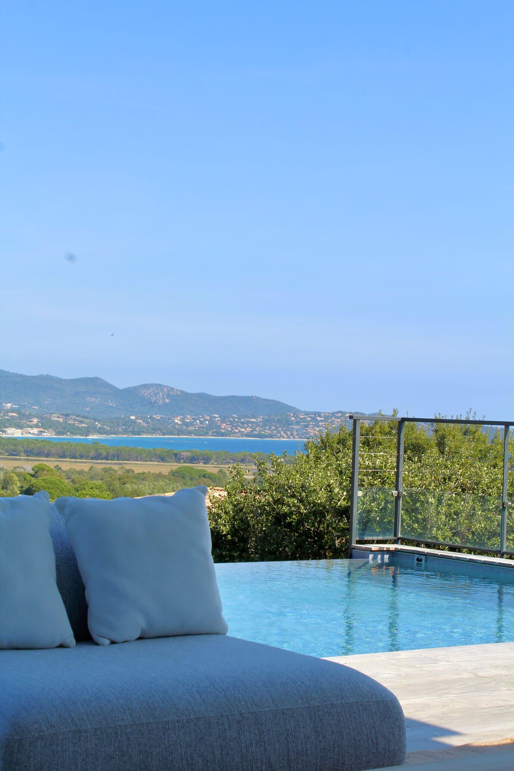 A pool with a clear view of the sea and hills in the background.