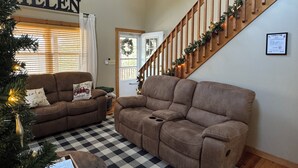 A living room with two brown sofas, a checkered rug, a Christmas tree, and a staircase with garlands. -  Spacious mountain home in Helen Georgia! Innsbruck community HOT TUB! FIRE PIT! (Helen)