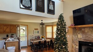 A cozy living room with a fireplace, a dining area, and a kitchen with wooden cabinets. -  Spacious mountain home in Helen Georgia! Innsbruck community HOT TUB! FIRE PIT! (Helen)