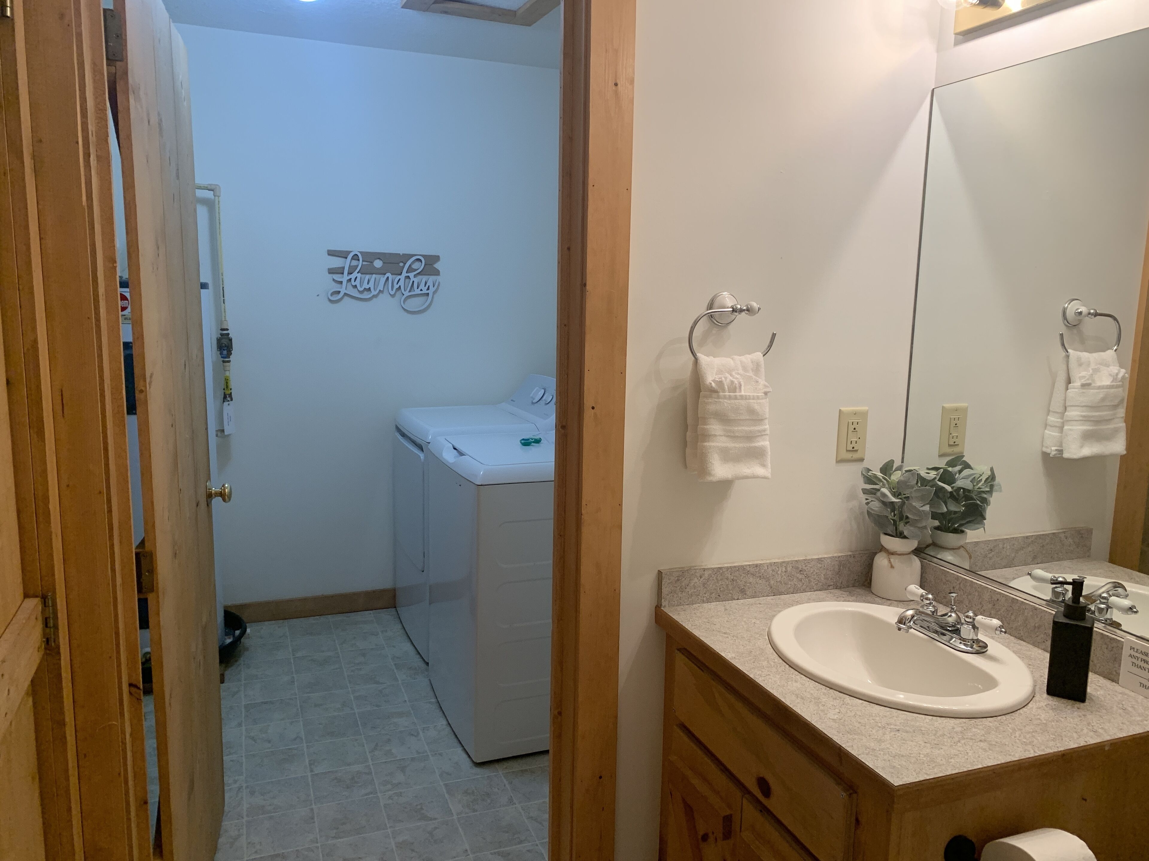 A bathroom with a sink, mirror, towel rack, and a wall-mounted sign.