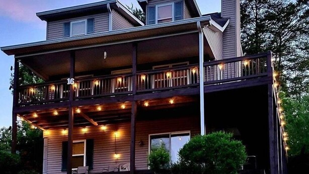 A two-story house with a covered porch and string lights. -  Spacious mountain home in Helen Georgia! Innsbruck community HOT TUB! FIRE PIT! (Helen)