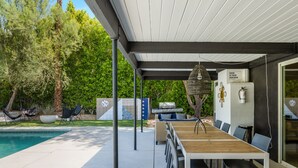 Eine Terrassenanlage im Freien mit Pool, Holztisch und Stühlen.