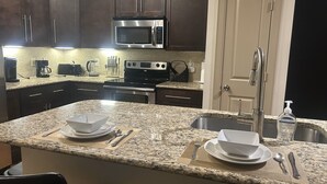 A kitchen with granite countertops, stainless steel appliances, and dark wooden cabinets. - Cool haven in the city, close to the medical center and NRG. (Houston)