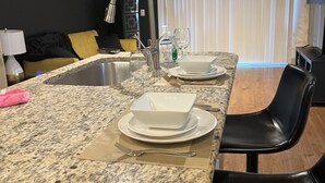 A kitchen with granite countertops, a sink, and a dining area with a black chair. - Cool haven in the city, close to the medical center and NRG. (Houston)