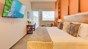 Ein modernes Schlafzimmer mit einem großen Bett, einem flachbildfernseher an der Wand, Blick auf die Stadt durch das Fenster und einem kleinen Tisch mit einer Pflanze.