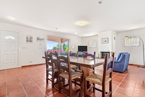 A dining area with a wooden table and chairs, a television, and a blue sofa.