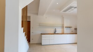 A modern kitchen with white cabinetry, a wooden countertop, and a built-in sink. - Villa "The Beach" with Sea View, Shared Terrace & Wi-Fi (Pittulongu)