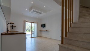 A spacious room with a staircase, a flat-screen TV mounted on the wall, and a sliding glass door leading to an outdoor area. - Villa "The Beach" with Sea View, Shared Terrace & Wi-Fi (Pittulongu)