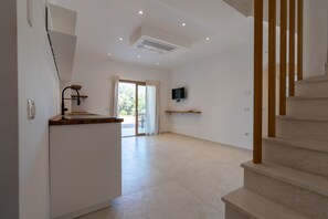 A spacious room with a kitchen area, a staircase, and a television mounted on the wall. - Villa "The Beach" with Sea View, Shared Terrace & Wi-Fi (Pittulongu)