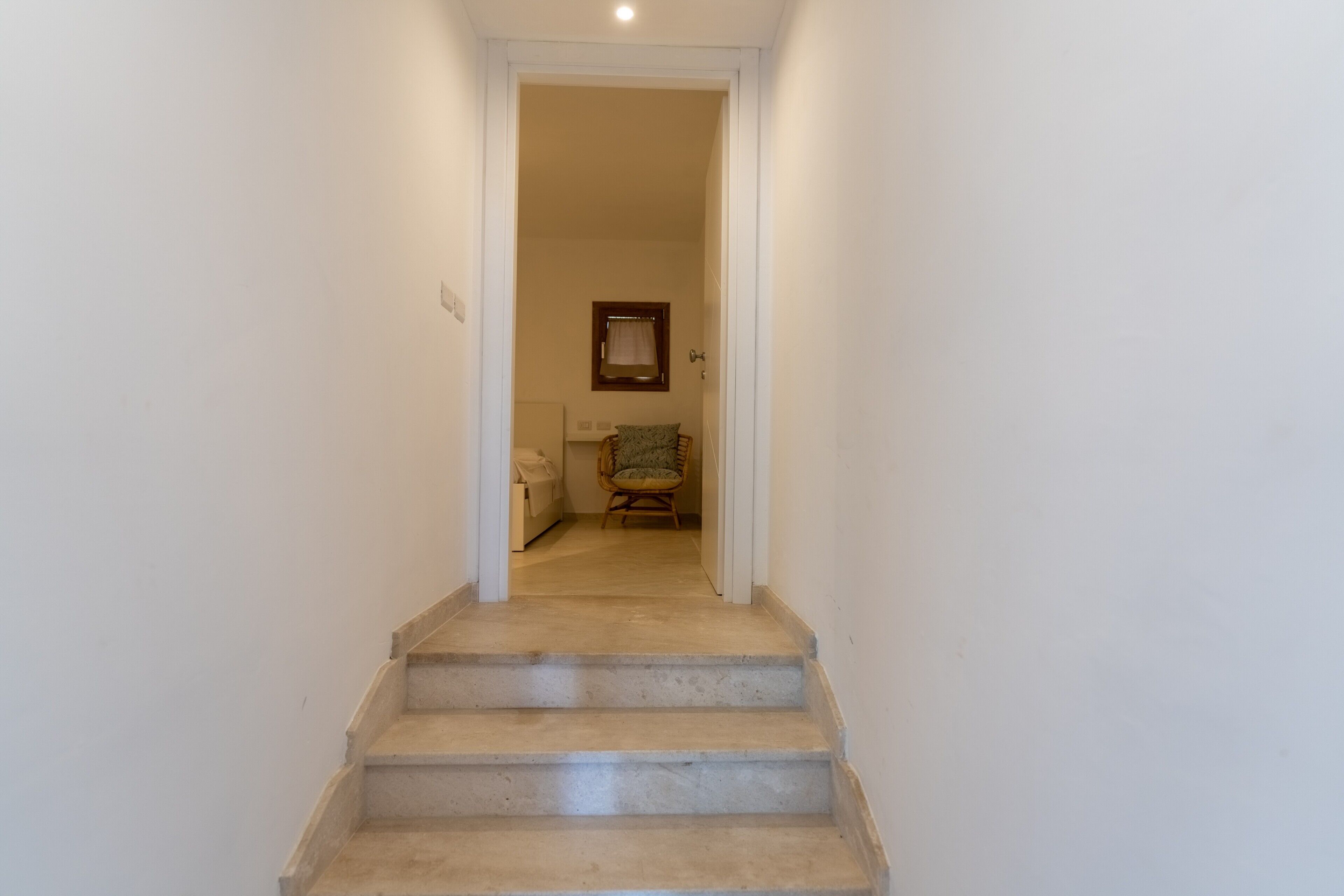 A staircase leading to a room with a bed, a chair, and a window.