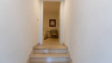 A staircase leading to a room with a bed, a chair, and a window.