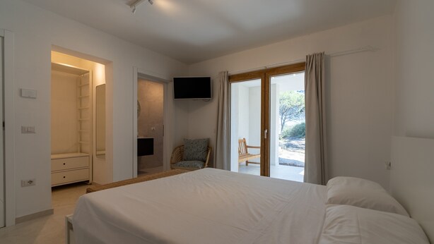 A bedroom with a bed, a TV, a chair, and a sliding glass door to the outside. - Villa "The Beach" with Sea View, Shared Terrace & Wi-Fi (Pittulongu)
