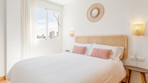 Un dormitorio con una cama grande, un adorno circular en la pared y dos lámparas fijadas a la pared.
