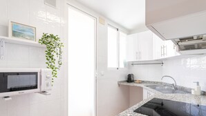 Una cocina moderna con armarios blancos, microondas integrado, encimera de granito y cocina de inducción negra.