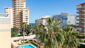 Un hotel de gran altura con varios balcones, piscina y palmeras.