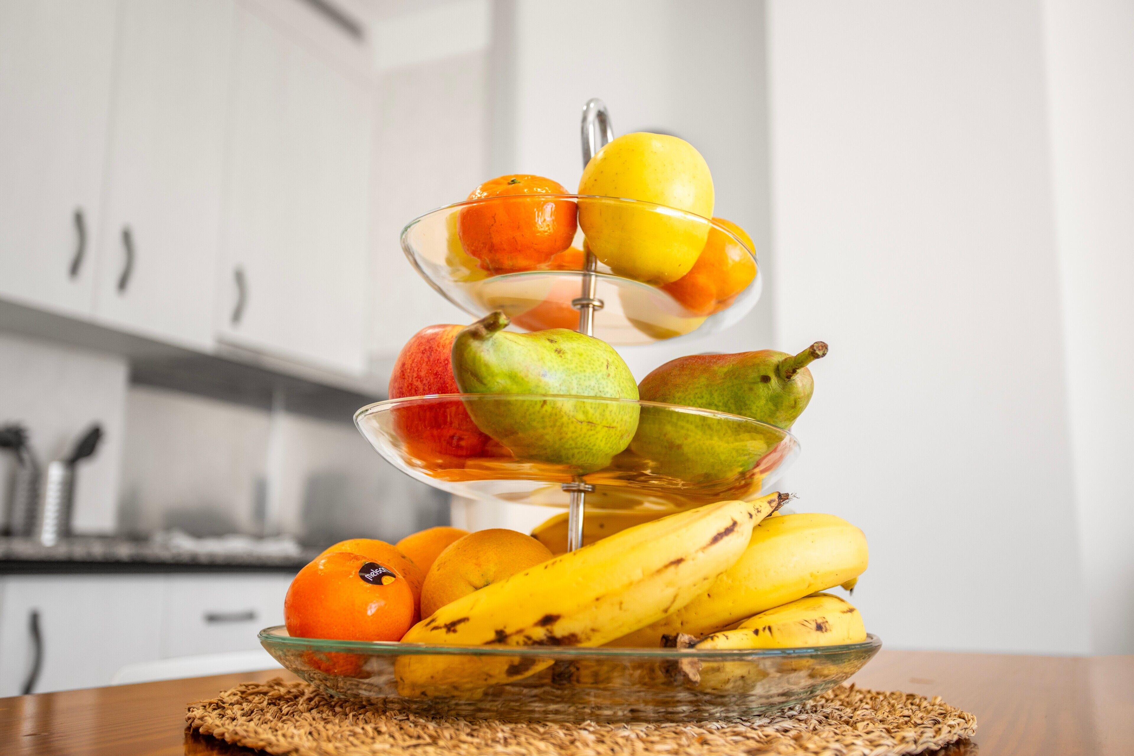 Un puesto de frutas de tres niveles con naranjas, manzanas, peras y plátanos.
