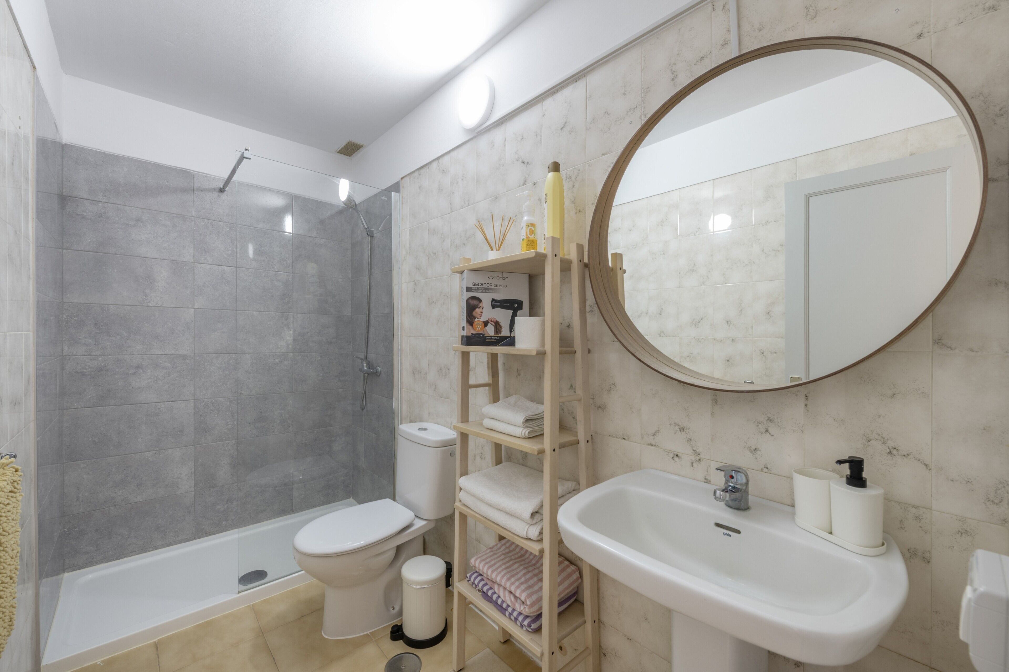 A modern bathroom with a shower, toilet, sink, and a mirror.